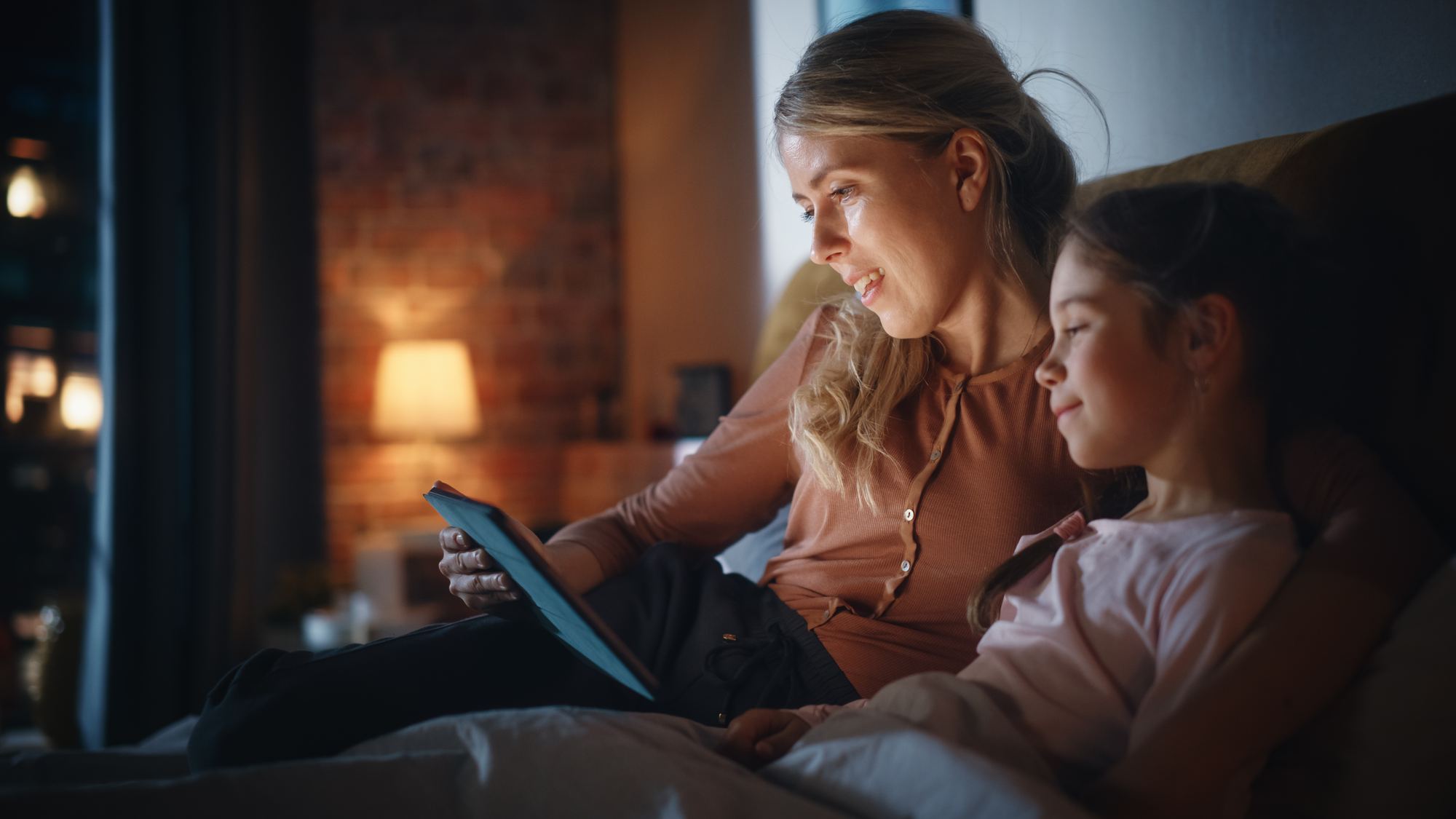 A parent and child reading from a tablet together